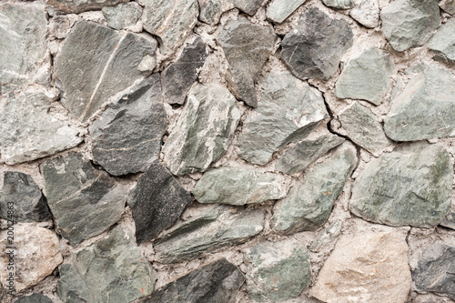 Close-up wall of uneven rough uncouth gray stones.