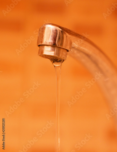 Water flowing from the tap in orange background, save water!