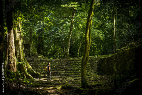 Woman stands in think jungle with a backpack on for female solo adventure travel concept photo
