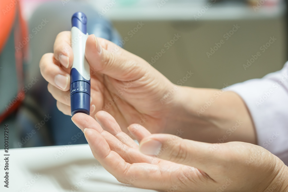Close up of man hands using lancet on finger to check blood sugar level by Glucose meter using as Medicine, diabetes, glycemia, health care and people concept. Close up of man hands using lancet on finger to check blood sugar level by Glucose meter using as Medicine, diabetes, glycemia, health care and people concept.