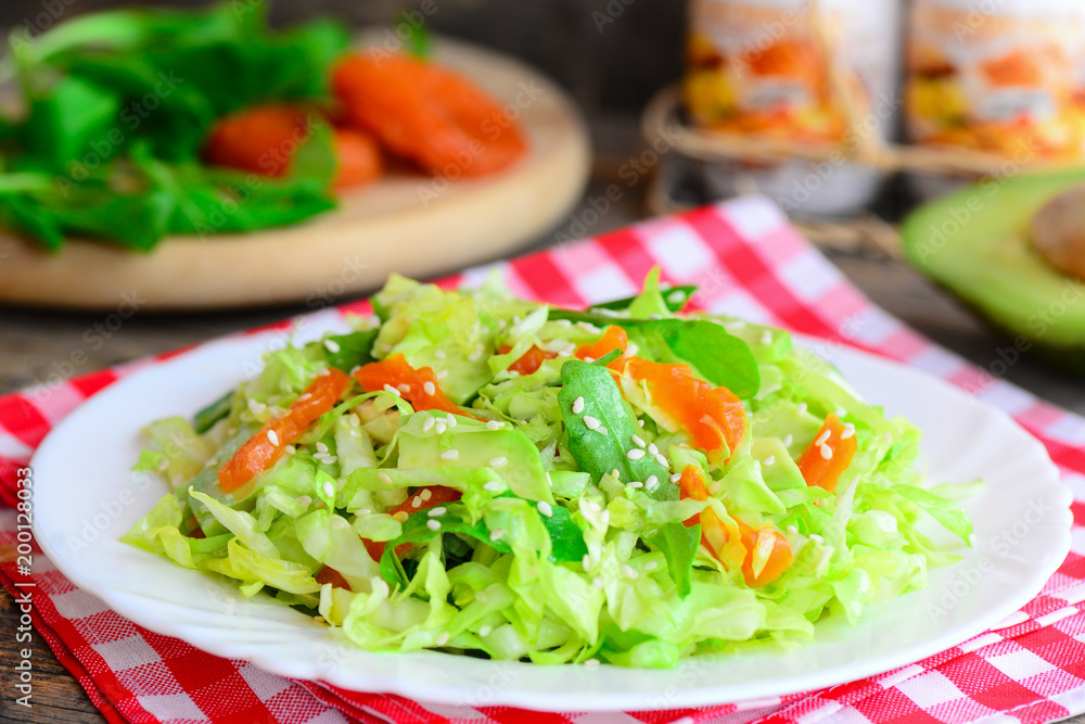 Simple сabbage salad with avocado. Home cabbage salad avocado, dried apricots, arugula and sesame on a plate and on a wooden table. Raw vegetarian salad. Raw food vegan diet. Closeup