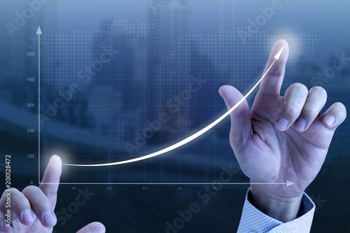 Close up of a businessman’s hands drawing an exponential line curve showing of business growth and success rapidly.