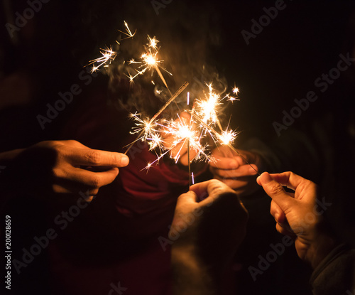Group of happy people holding sparklers at party and smiling.