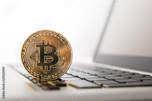 Golden Bitcoin - New virtual money on notebook. A visual representation of digital cryptocurrencies. Bitcoin are fully dematerialized and decentralized electronic currencies. Shallow depth of field. photo