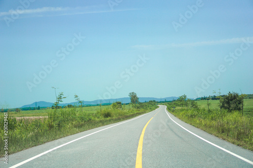 Road through green meadows, travel concepts or travel. © waraphot