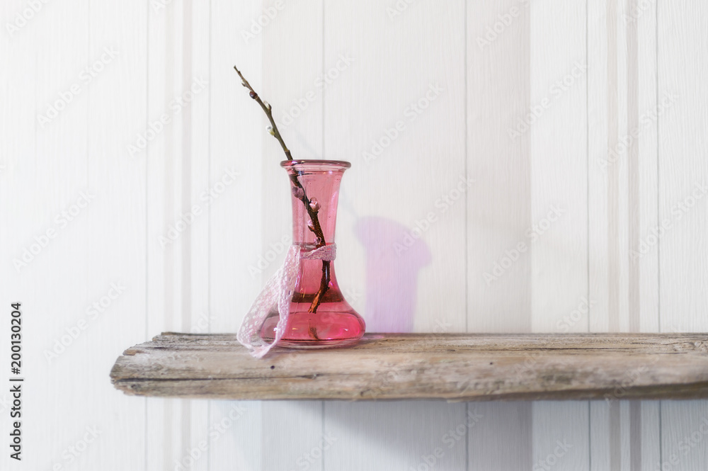 Φωτογραφία Pinke Glasflasche mit Weidenkätzchen  Ast steht auf altem Holz vor heller Tapete