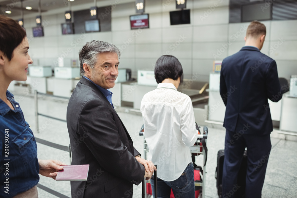 Passengers waiting in queue at a check-in counter with luggage Passengers waiting in queue at a check-in counter with luggage