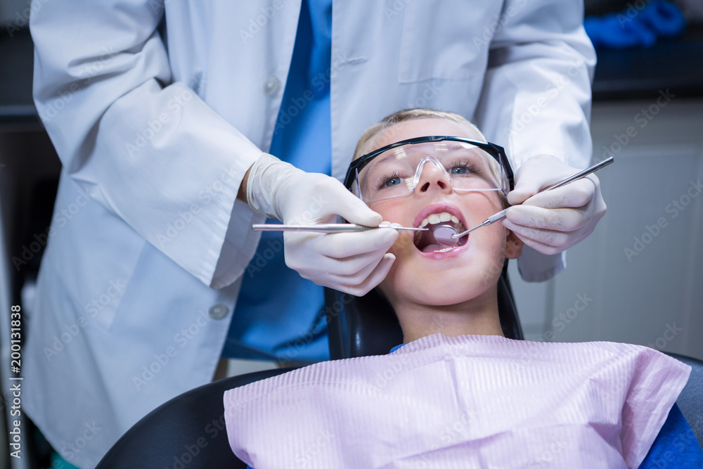 Dentist examining a young patient with tools Dentist examining a young patient with tools