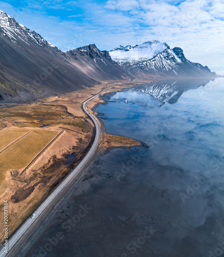 High angle aerial view of a road by ocean leading towards distance with snow covered mountains in Iceland at spring © Jamo Images