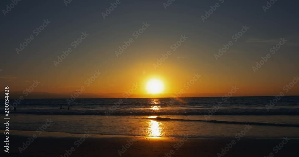 Family plays in the ocean under a beautiful dramatic sunset on the beach. Family plays in the ocean under a beautiful dramatic sunset on the beach.