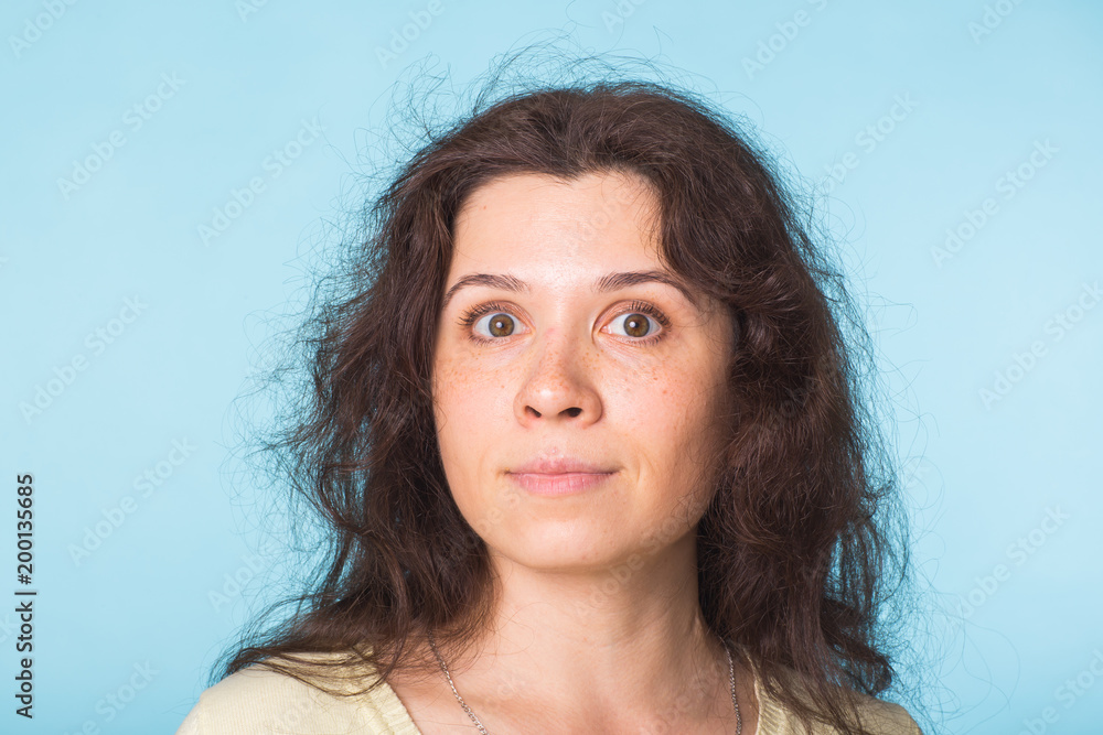 Close up portrait of a beautiful young woman with curly hair on blue background