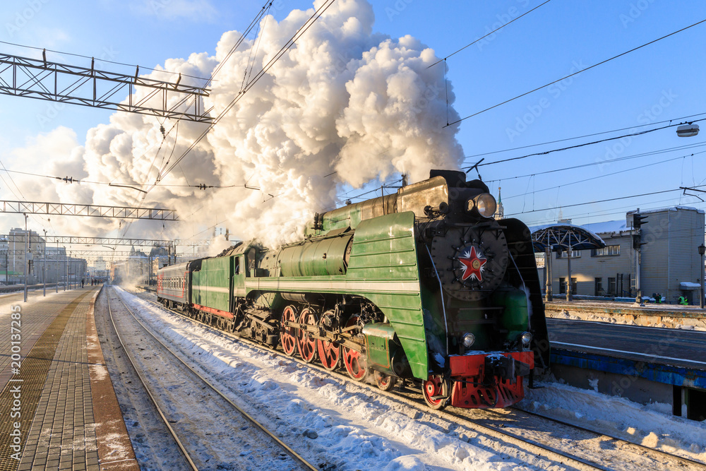 Obraz premium stary czarny parowóz w Rosji zimą na tle moskiewskiego dworca kolejowego