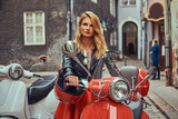 Sexy blonde girl wearing stylish clothes standing on an old street with two retro scooters.