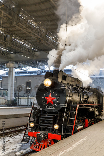 old black steam locomotive in Russia in the winter on the background of the Moscow railway station
