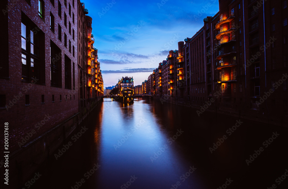 Blue hour in Warehouse District - Speicherstadt. Tourism landmark of Hamburg in twilight. View of Wandrahmsfleet in lantern light lamp. Place is located in Port of Hamburg within the HafenCity quarter