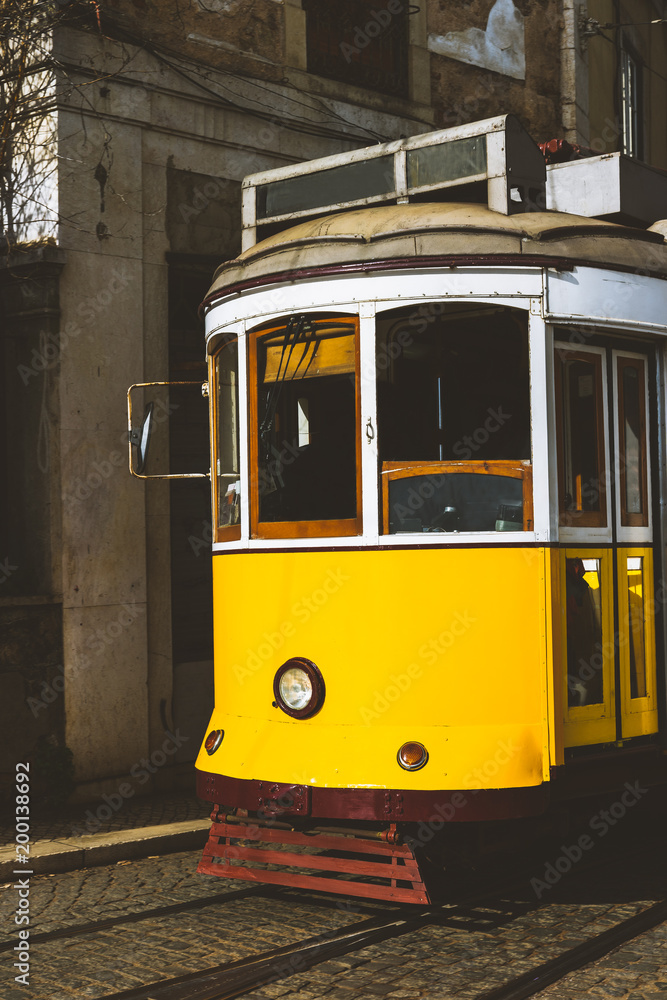 Quaint yellow tram on the rails of old and beautiful street of Alfama District of Lisbon. City touristic landmarks of Lisboa Lissabon