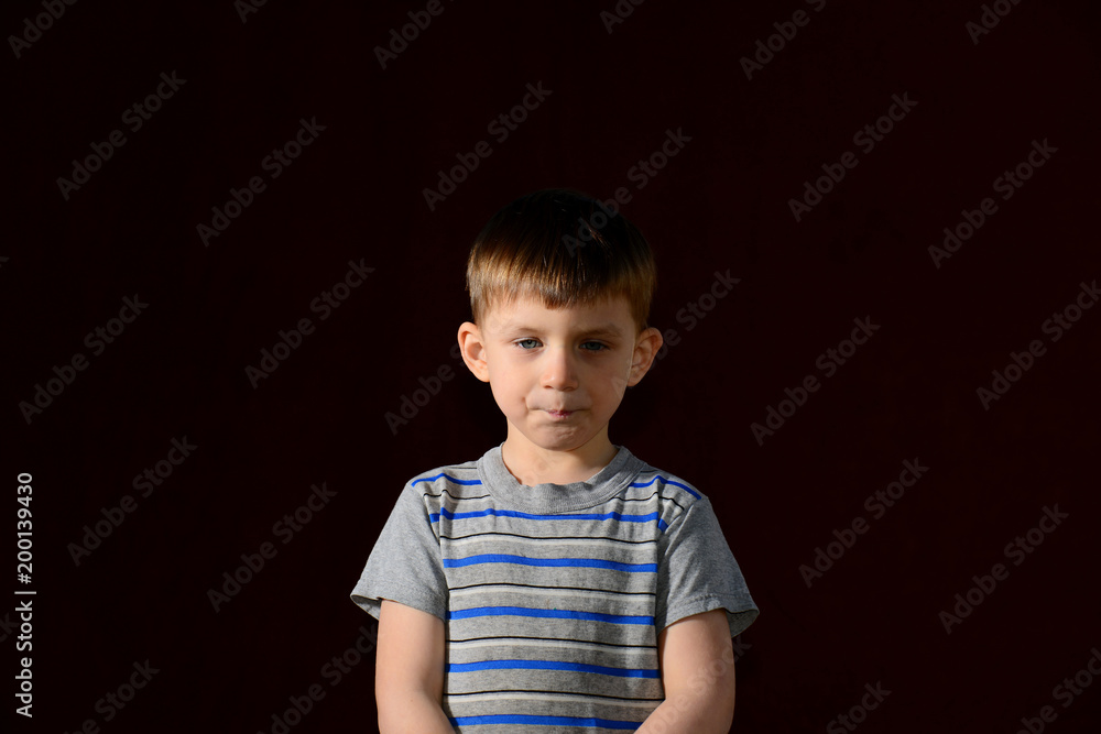 Portrait of a boy on a dark background in the studio, one side is lit up by more than another Portrait of a boy on a dark background in the studio, one side is lit up by more than another