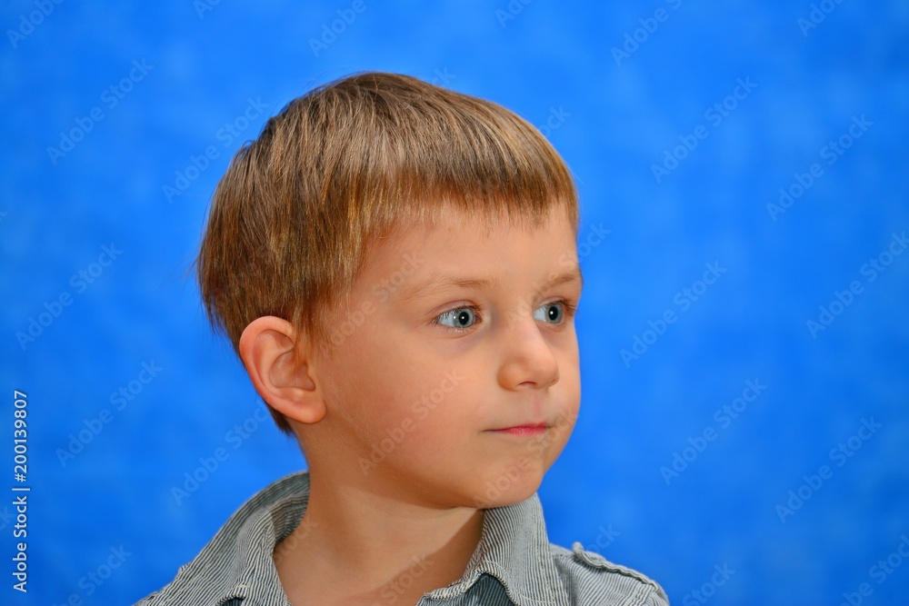 Boy in the studio on a blue background looking out into the distance Boy in the studio on a blue background looking out into the distance