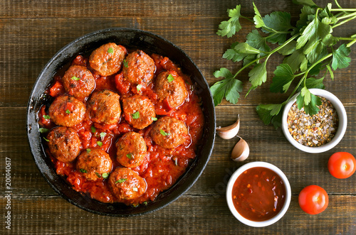 Meatballs in cast iron pan, fresh parsley and tomatoes
