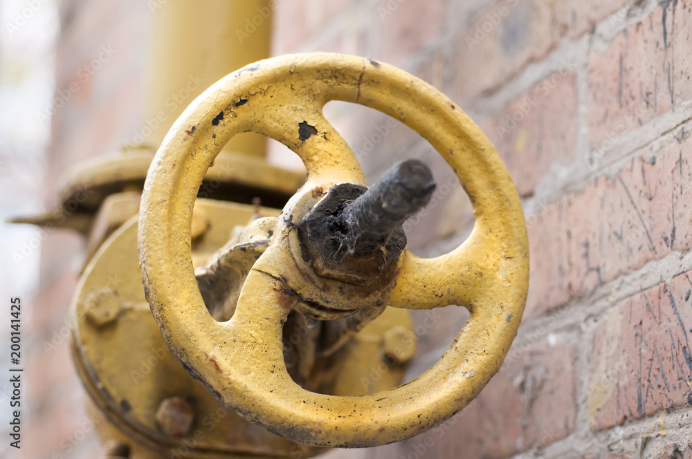 An old rusty gas control valve on the wall. An old rusty gas control valve on the wall.