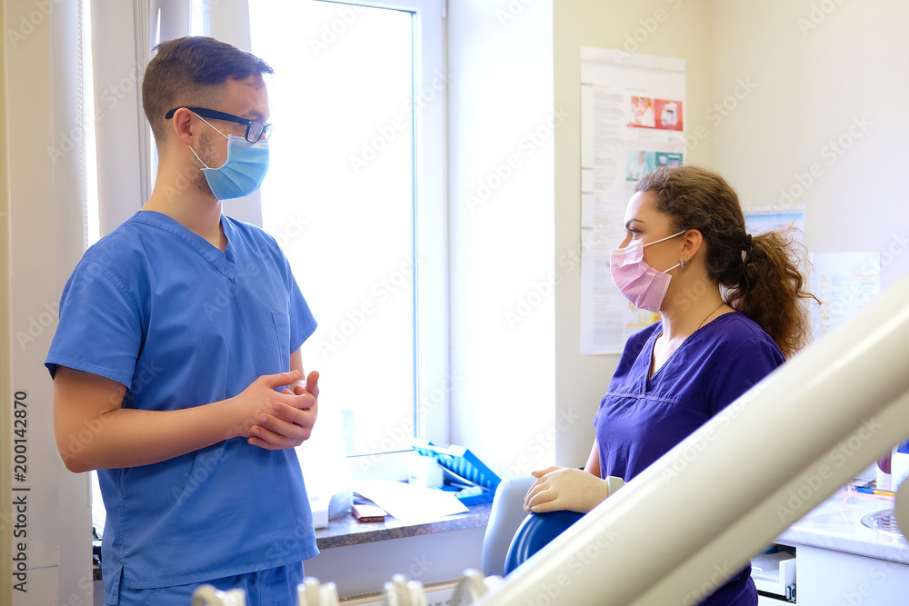 Fototapeta premium Handsome male dentist speaks with a female assistant at a clinic.