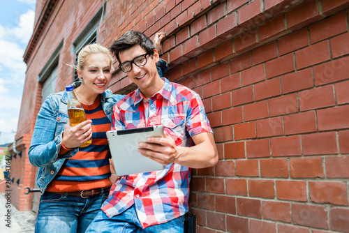 Couple, woman and man, on holidays organizing their Berlin sightseeing tour with tablet PC on rooftop terrace photo