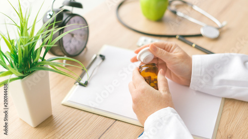 Tableau sur toile Female doctor holding unlabeled bottle of various pills and medication