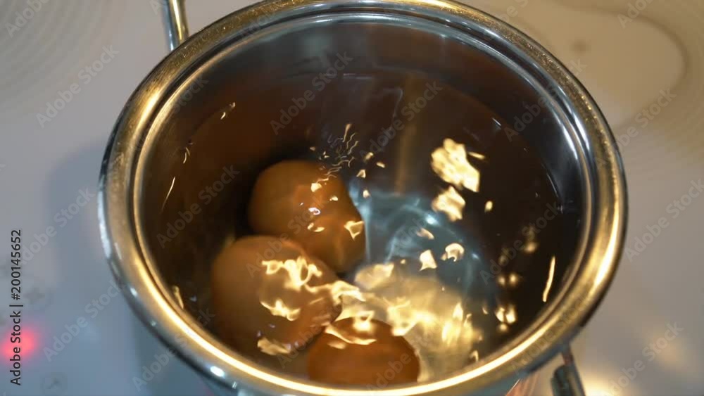 hand puts eggs in a pan with water to cook hand puts eggs in a pan with water to cook