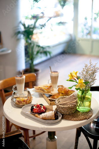 delicious breakfast for two at the luxury hotel with fresh hot pie, tart with berry jam, croissant and coffee cappuccino on light table. Cafe brunch.close up