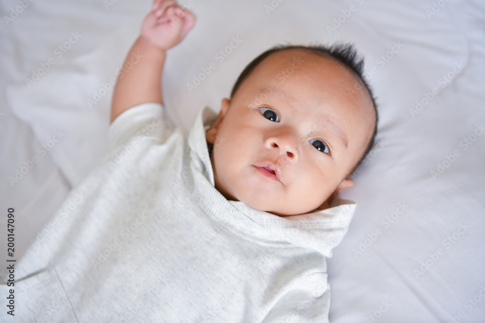 Newborn Concept. Mother and child on a white bed. Mom and baby boy playing in bedroom. Parent and little kid relaxing at home. Family having fun together. Newborn baby is fussing and crying. Newborn Concept. Mother and child on a white bed. Mom and baby boy playing in bedroom. Parent and little kid relaxing at home. Family having fun together. Newborn baby is fussing and crying.