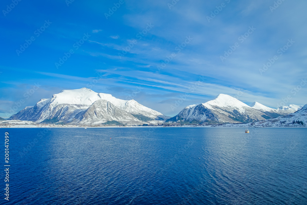 Amazing landscape of coastal scenes of huge mountain covered with snow on Hurtigruten during voyage in a blue sky