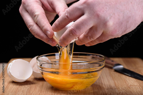 Man hands breaking an egg egg shells at the cutting board