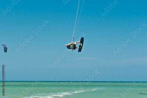 Front view of a young male, lifting out of water and spinning while kiteboarding at fast speed through rough ,tropical water of the Gulf of Mexico