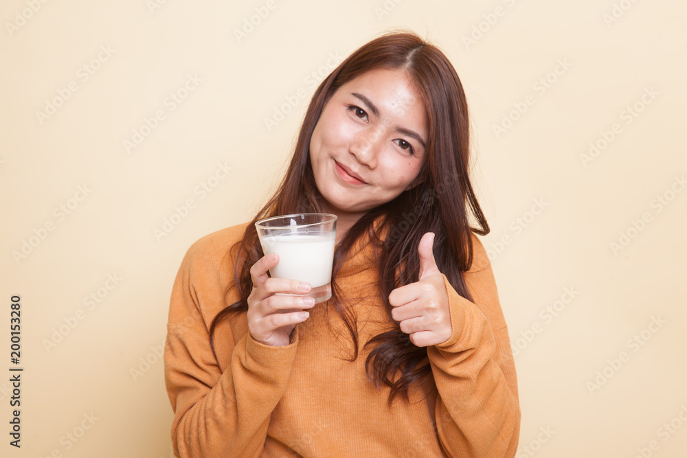 Healthy Asian woman drinking a glass of milk thumbs up. Healthy Asian woman drinking a glass of milk thumbs up.
