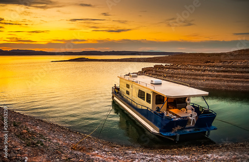 Beautiful and scenic landscape of the Lake Mead National Recreation Area with a houseboat moored to the shores of a bay with a dramatic sky at sunset, Nevada. Vacation and tourism concept., copy space photo
