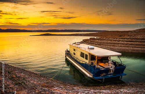 Valokuva Beautiful and scenic landscape of the Lake Mead National Recreation Area with a houseboat moored to the shores of a bay with a dramatic sky at sunset, Nevada