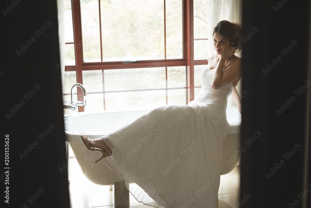Bride in wedding dress posing near bathtub Bride in wedding dress posing near bathtub