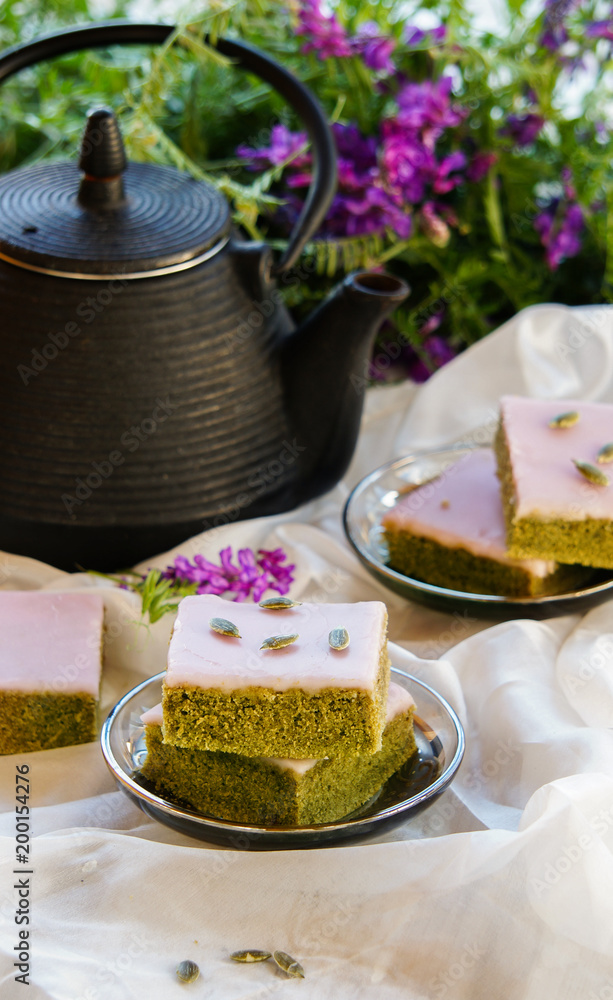 Matcha green tea cakes with white chocolate glaze seeds with tea on the white background Matcha green tea cakes with white chocolate glaze seeds with tea on the white background