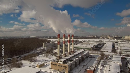 Aerial fly over view near city district power plant smoke steam pipes in sunny winter day