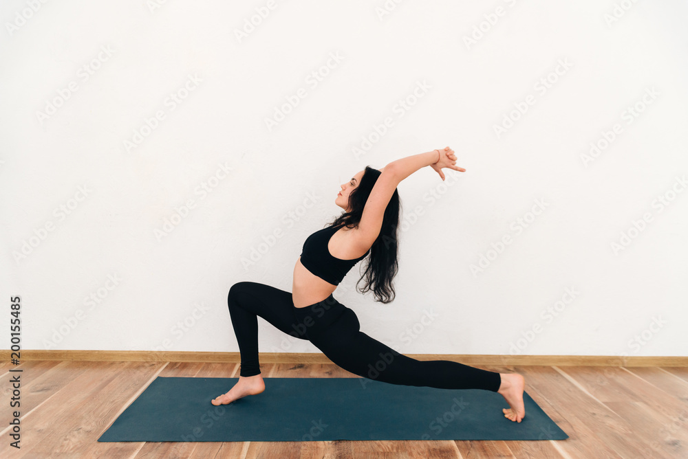 Young attractive woman practicing yoga, standing in anjaneyasana exercise, Horse rider pose, working out, wearing sportswear, full length, isolated, white studio background