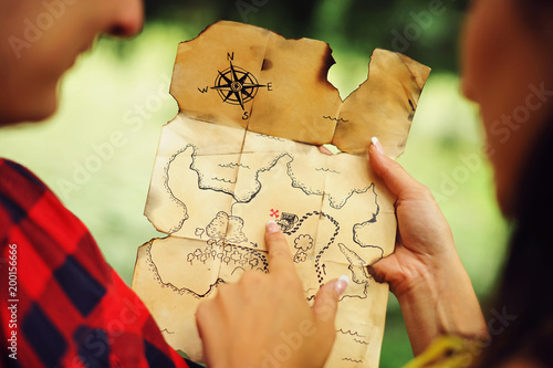 Картината върху платно Couple of lovers holding a pirate map in hands and looking for treasures
