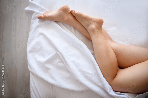 crossed woman legs on bed in bedroom.