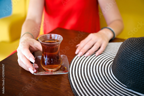 women in red dress and hand with turkish tea on the wooden table and hat .