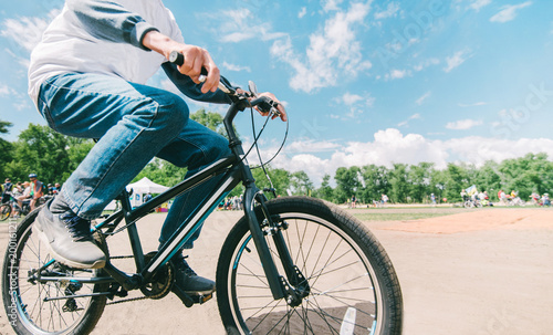 Hipster s husband rides a bike in sunny summer weather. Walking in the park on a bike. Close-up bike. Active leisure concept.