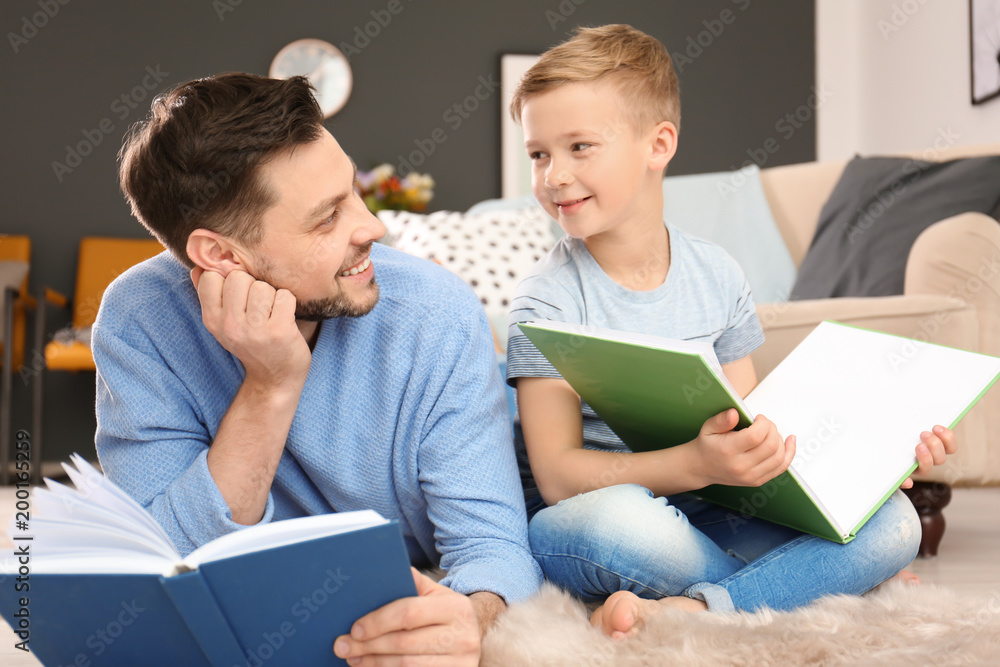 Little boy and his dad reading books at home Little boy and his dad reading books at home