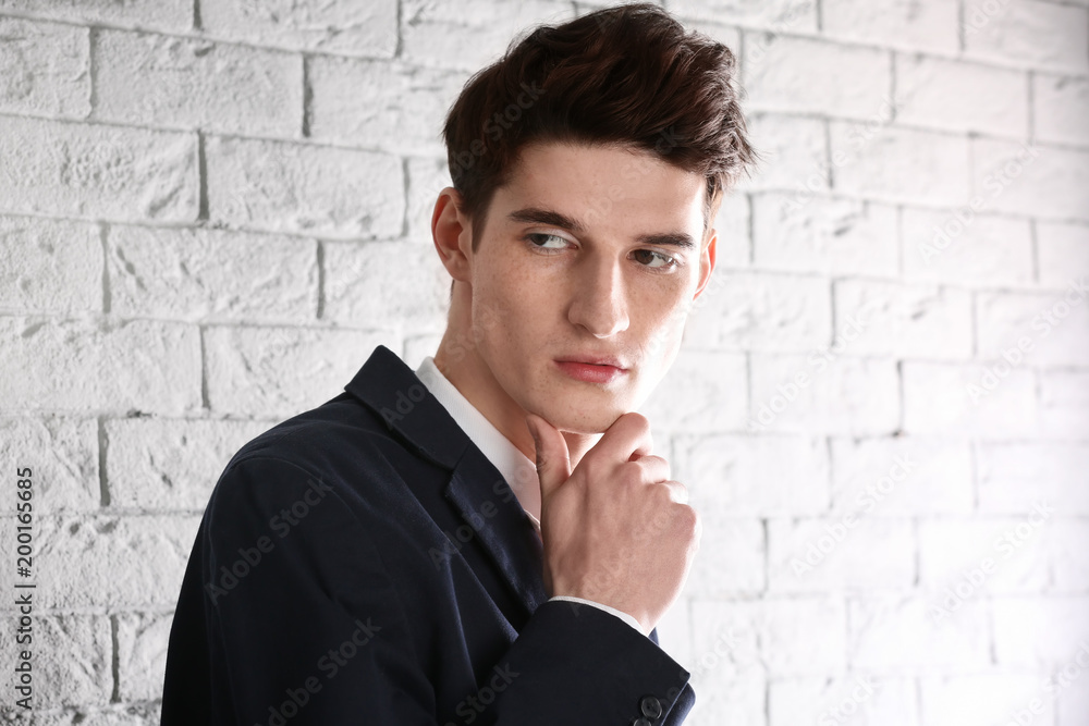 Portrait of young businessman with beautiful hair on brick wall background Portrait of young businessman with beautiful hair on brick wall background
