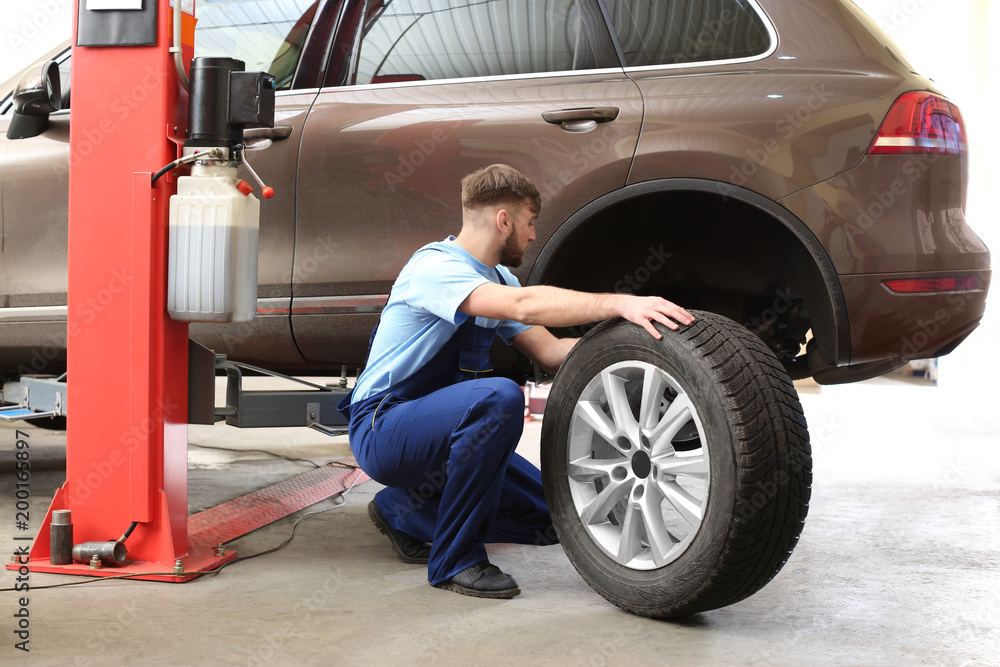Mechanic changing car wheel in garage. Tire service Mechanic changing car wheel in garage. Tire service