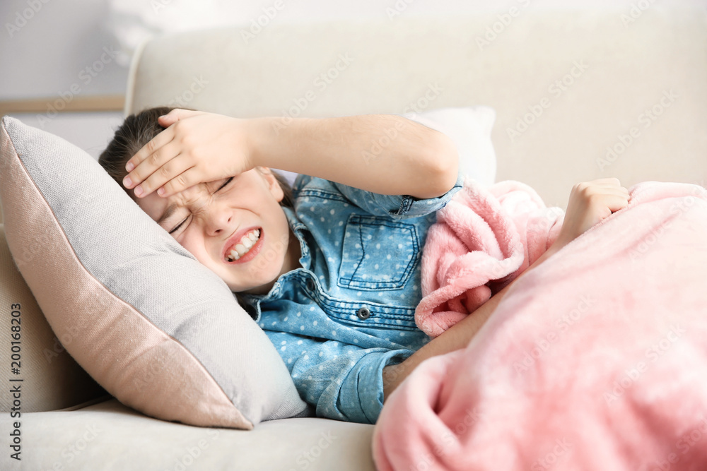 Little girl suffering from headache while lying on couch at home Little girl suffering from headache while lying on couch at home