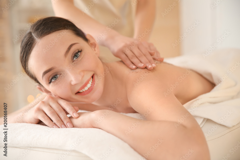 Beautiful young woman having massage with body scrub in spa salon Beautiful young woman having massage with body scrub in spa salon