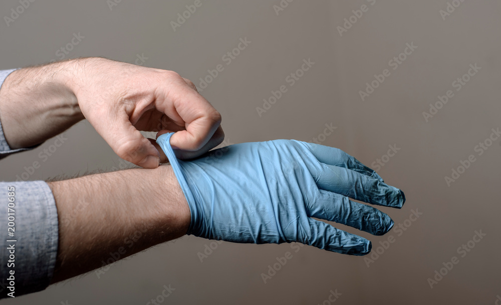 Fototapeta premium man putting on a pair of latex gloves
